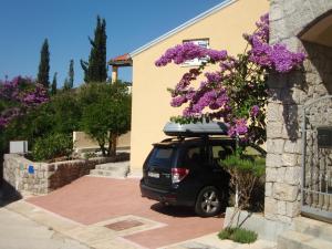 um carro estacionado ao lado de um edifício com flores roxas em Apartment Luna em Molunat