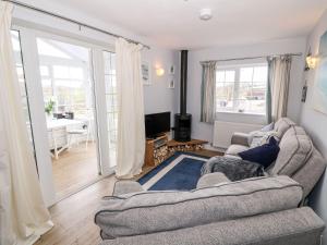a living room with a couch and a television at Ty Bach, 1 bedroom home with hot tub and views in Bettws-yn-Rhôs