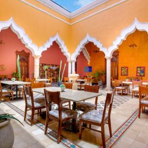 un restaurante con paredes de color naranja, mesas y sillas en Viva Merida Hotel Boutique, en Mérida