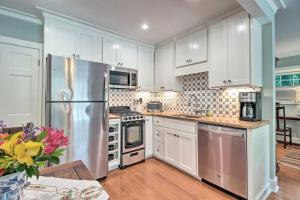 a kitchen with white cabinets and a stainless steel refrigerator at Elegant Savannah Hideaway with Private Garden in Savannah