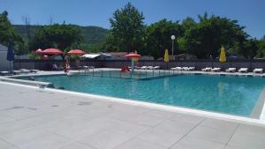 une grande piscine avec des chaises et des parasols dans l'établissement mobil-home du lac de Foix, à Foix