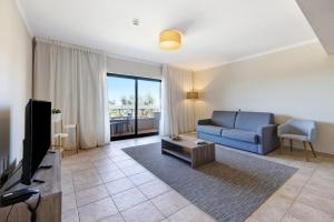 a living room with a blue couch and a tv at Pestana Gramacho Residence T1 in Carvoeiro