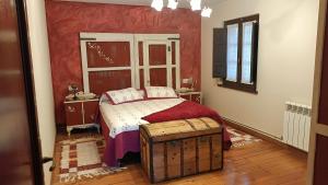 a bedroom with a bed with a red wall at Casa Joglar in Beceña