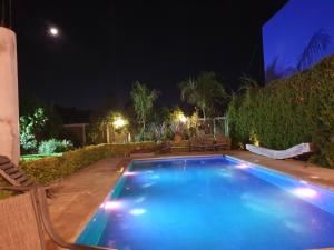 a swimming pool at night with chairs around it at CASA GUME - Departamentos con 2 habitaciones para 4 personas in Oaxaca City