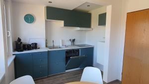 een kleine keuken met blauwe kasten en een wastafel bij Friesenmeer Ferienwohnung Vier in Bensersiel