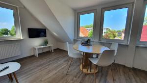 Habitación con mesa, sillas y ventanas. en Friesenmeer Ferienwohnung Vier, en Bensersiel