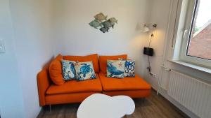 an orange couch in a room with a window at Friesenmeer Ferienwohnung Vier in Bensersiel