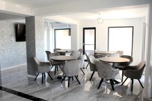 a group of tables and chairs in a room with windows at Ren Litoral in Năvodari