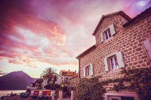 un edificio junto a un cuerpo de agua con puesta de sol en Luxury 6 bedroom house on waterfront, en Perast