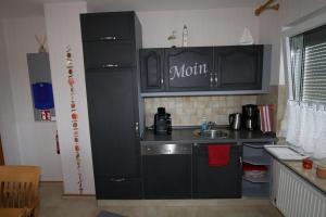 eine Küche mit schwarzen Schränken und einem Waschbecken in der Unterkunft Frankenhuus in Krummhörn
