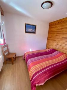 1 dormitorio con 1 cama grande y 1 silla en La Foux 2 pièces, en Allos