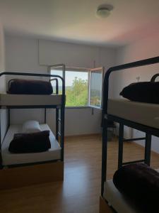 a room with three bunk beds and a window at Albergue Alto da Pena EXCLUSIVE FOR PILGRIMS in Negreira