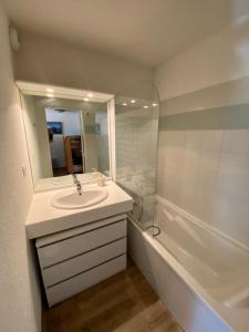 La salle de bains est pourvue d'un lavabo, d'un miroir et d'une baignoire. dans l'établissement La Foux 2 pièces, à Allos