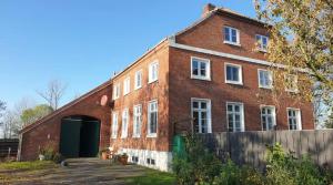 a large red brick building with a green door at Grashaus Upleward in Krummhörn