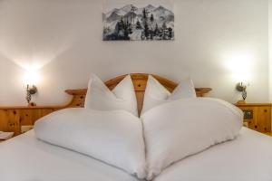 uma cama com almofadas brancas em cima em Hotel Hubertushof em Grossarl