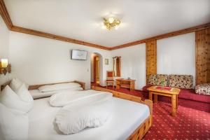 um quarto de hotel com duas camas e um sofá em Hotel Hubertushof em Grossarl