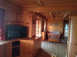 a living room of a log cabin with a flat screen tv at Un bel panorama in un ambiente famigliare in Tesero