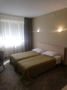 a hotel room with two beds and a window at Hotel Senas Namas in Alytus