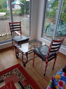 dwa krzesła i stół w pokoju z oknem w obiekcie Jandyal Farm House w mieście Malshej Ghat