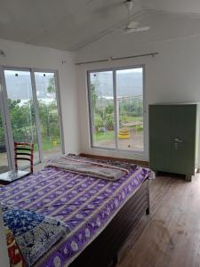 a bedroom with a bed and a large window at Jandyal Farm House in Malshej Ghat