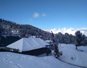 a tent is covered in snow in a mountain at Camping at Serene Chopta in Sari