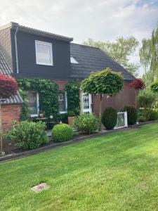 une maison avec une pelouse verte devant elle dans l'établissement FeWo Landruhe, à Aurich