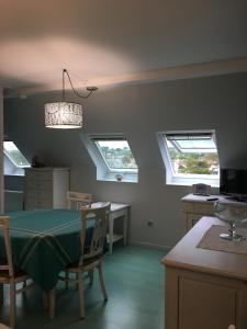 a dining room with a table and three windows at A 50m de la mer in Agon Coutainville