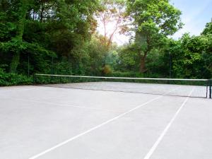 una pista de tenis con red y algunos árboles en VILLA AVEC PISCINE PRIVEE en Auberville