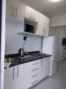 a white kitchen with a sink and a refrigerator at Grace Villas modern studio apartments in East London