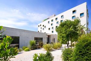 a large white building with a large white building behind it at Holiday Inn Express Montpellier - Odysseum, an IHG Hotel in Montpellier