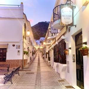 eine Gasse mit einer Bank in einer Stadt mit Gebäuden in der Unterkunft Sea to Sky Suites - Mijas Pueblo in Mijas