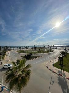 a street with a car driving down a road next to the ocean at Appartement luxe martil in Martil