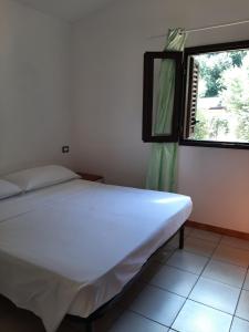 a white bed in a room with a window at Residence Eden in Marina di Camerota