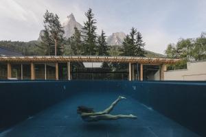 une femme se baignant dans une piscine avec des montagnes en arrière-plan dans l'établissement Sensoria Dolomites, à Alpe di Siusi