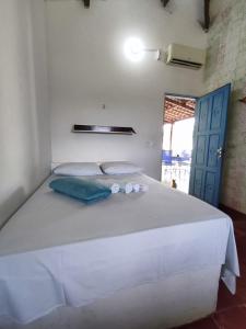 a bedroom with a large white bed with two pillows at Pousada e Restaurante Tremembé in Icapuí