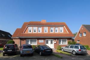 three cars parked in front of a brick house at Friesenmeer Apartment in Bensersiel