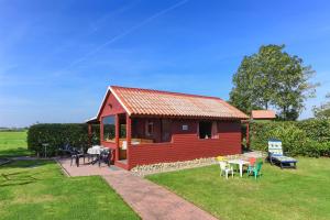 a red cabin with tables and chairs in a yard at Friesenmeer Apartment in Bensersiel