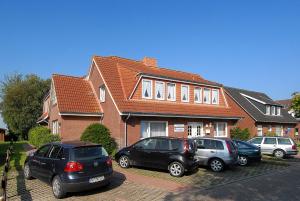 a group of cars parked in front of a house at Friesenmeer Apartment in Bensersiel
