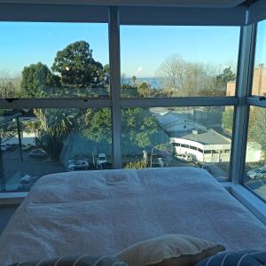 a bedroom with a bed and a large window at Ombu Loft Olivos, Vista al Rio in Olivos
