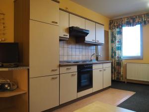 a kitchen with white cabinets and a stove top oven at Friesenmeer Apartment in Bensersiel +5 photos