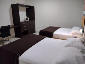 a bedroom with two beds and a desk and a mirror at Intiotel Piura in Piura