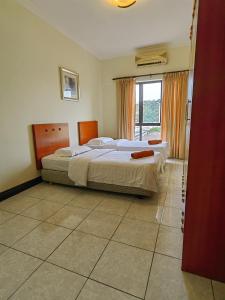 een slaapkamer met 2 bedden en een groot raam bij Marina Court Kota Kinabalu in Kota Kinabalu