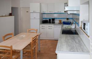 a kitchen with white cabinets and a wooden table and chairs at Maison de 3 chambres avec jardin clos et wifi a Channay sur Lathan in Channay-sur-Lathan