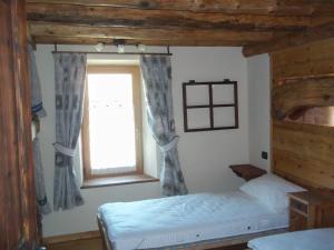 1 dormitorio con 2 camas y ventana en Alloggio Gran Paradiso, en Aosta