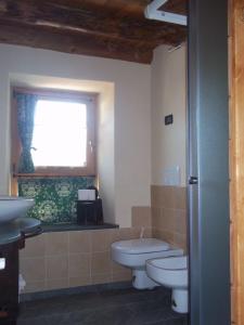 baño con 2 aseos, lavamanos y ventana en Alloggio Gran Paradiso, en Aosta