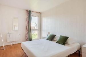 ein Schlafzimmer mit einem großen weißen Bett mit grünen Kissen in der Unterkunft Appartement à 10 minutes du centre de Paris avec le RER B in La Courneuve