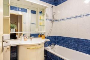 La salle de bains est pourvue de carrelage bleu, d'un lavabo et d'une baignoire. dans l'établissement Appartement à 10 minutes du centre de Paris avec le RER B, à La Courneuve