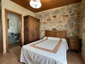 a bedroom with a bed and a stone wall at Casa La Colmena Ávila in Avila