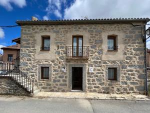Casa de piedra antigua con balcón en una calle en Casa La Colmena Ávila, en Ávila