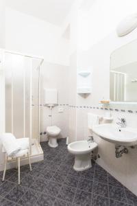 Baño blanco con 2 aseos y lavamanos en Hotel Residence Des Bains, en Cesenatico
